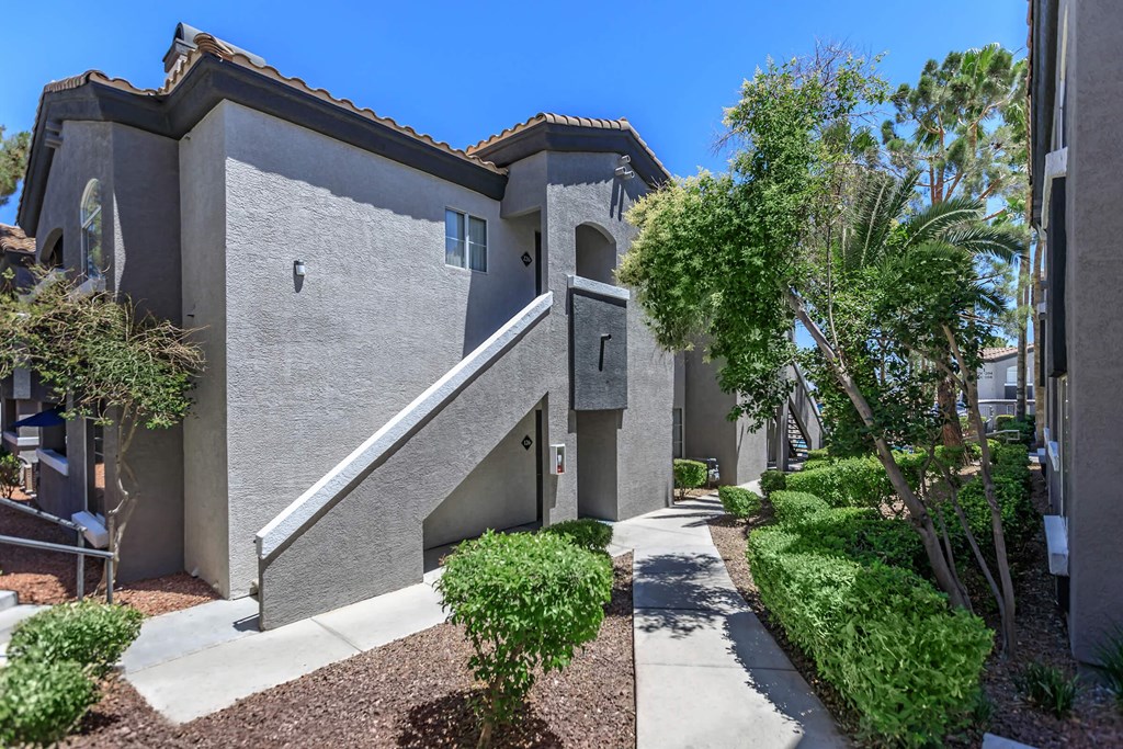 a house with a walkway and trees in front of it