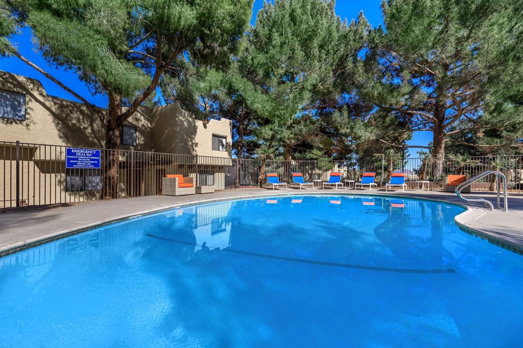 A large blue swimming pool surrounded by trees and a building.