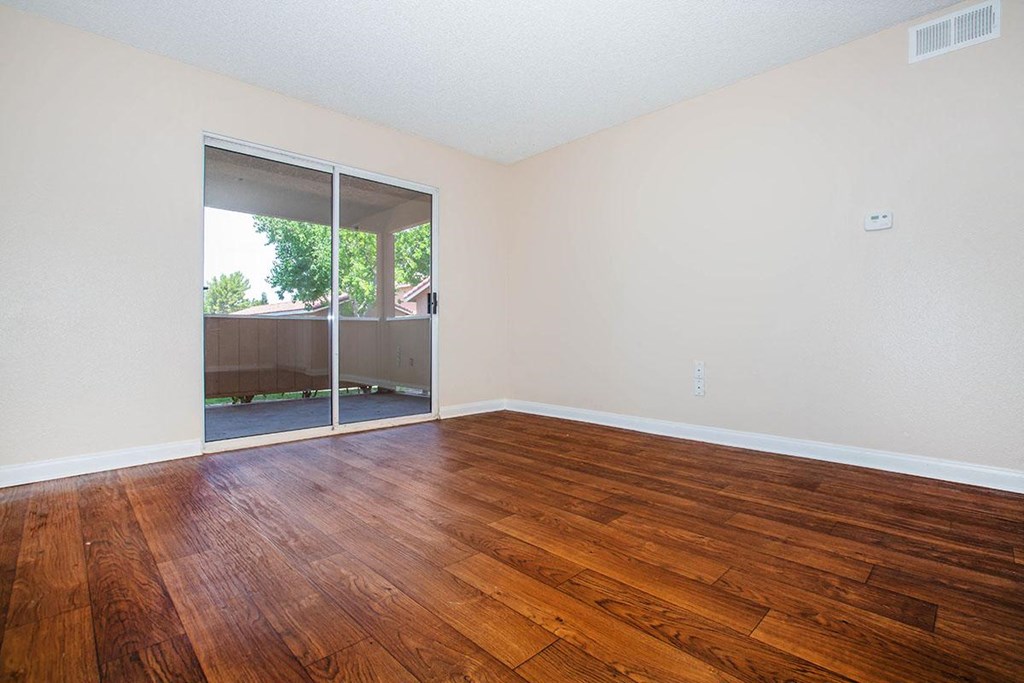 an empty living room with wood flooring and sliding glass doors