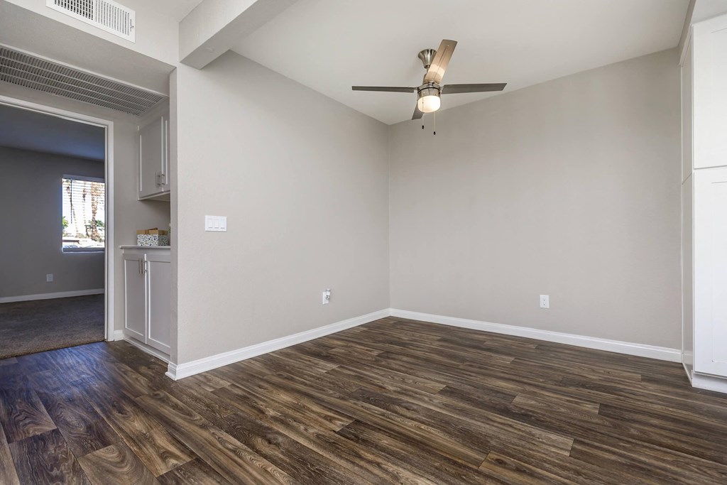 an empty living room with wood flooring and a ceiling fan
