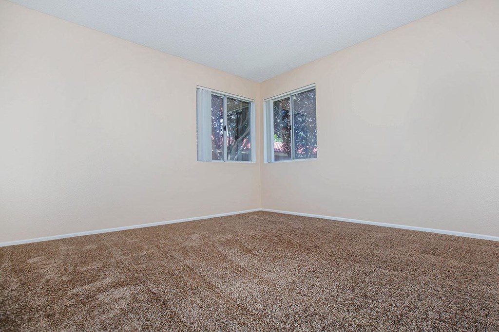 a empty room with carpet and two windows