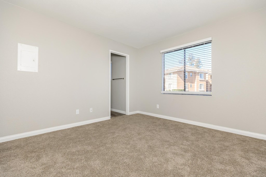 an empty living room with a window and carpet
