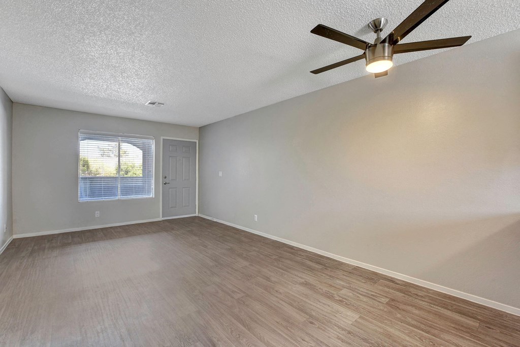 an empty living room with a ceiling fan and a window