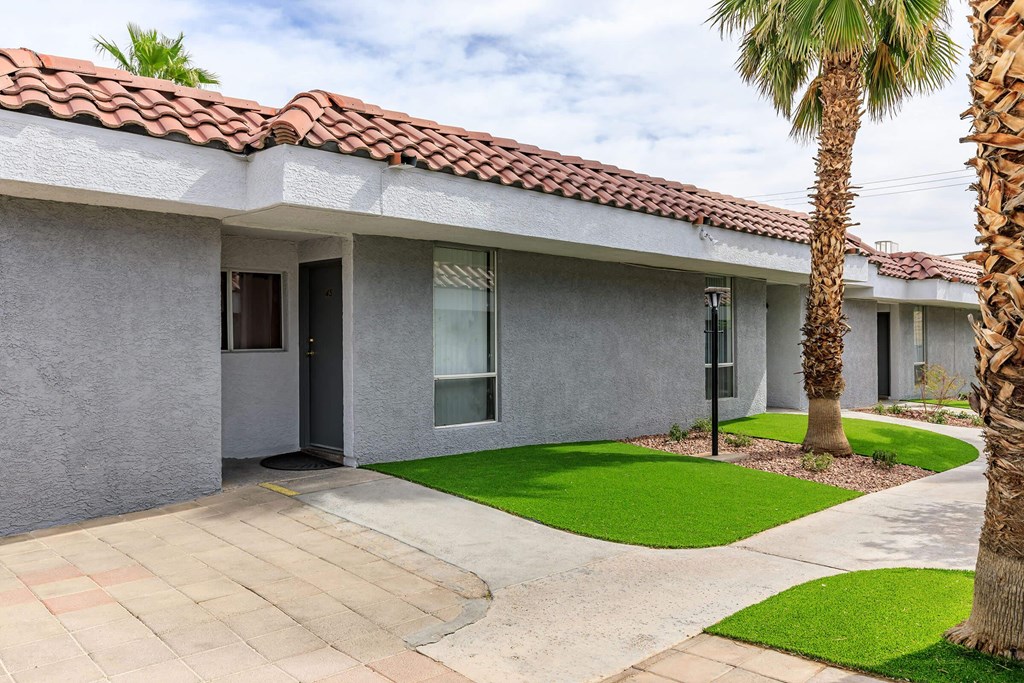 a white house with a sidewalk and palm trees