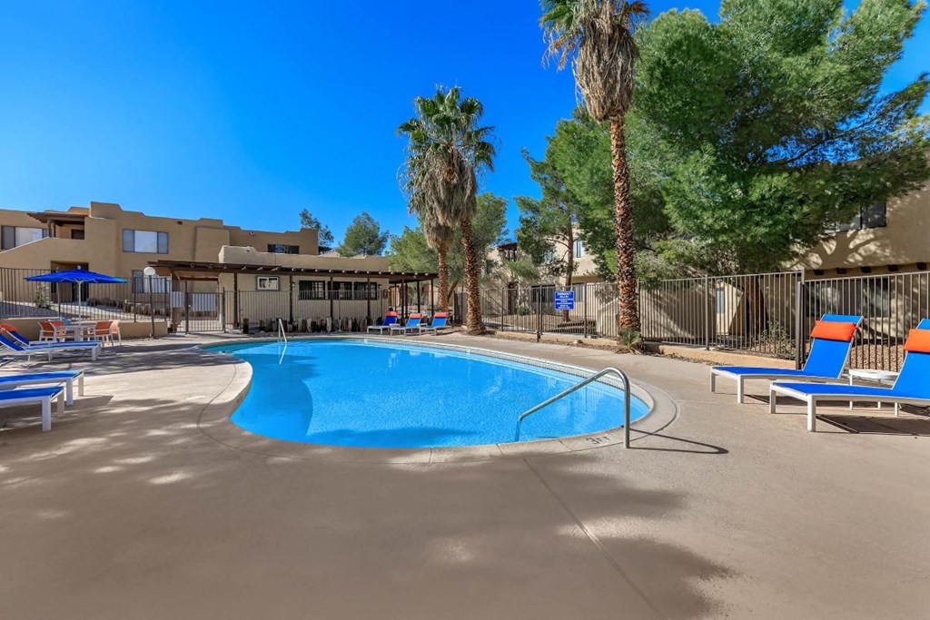 A swimming pool surrounded by palm trees and lounge chairs.