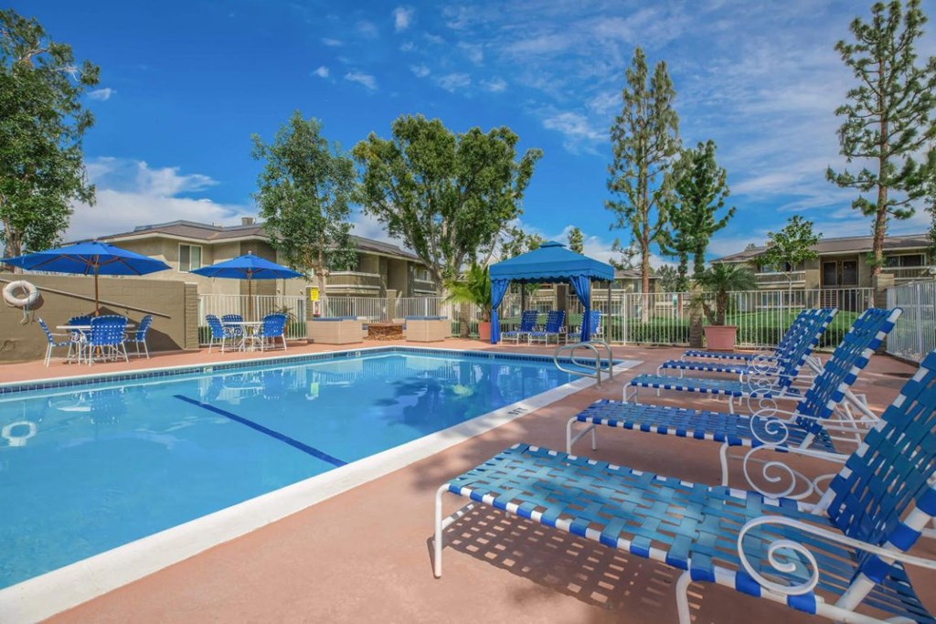 our apartments have a large pool with blue chairs and umbrellas
