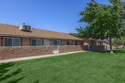 A house with a green lawn and a tree in front.