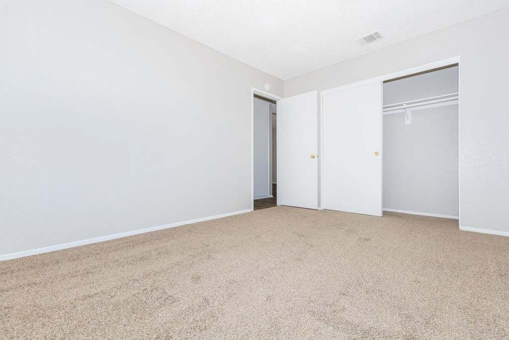 an empty bedroom with white walls and a closet