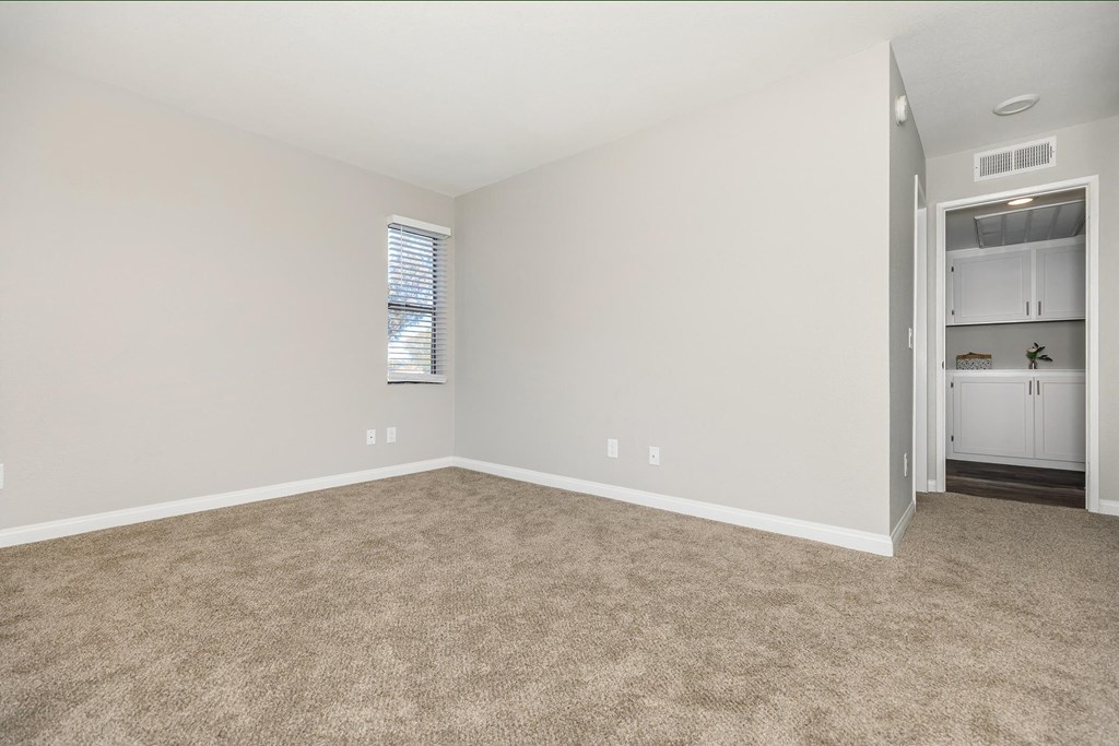 an empty living room with carpeting and a door to a bathroom