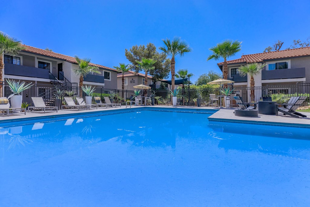 a large swimming pool with palm trees and apartments in the background