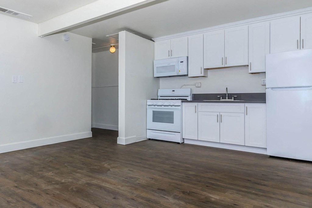 an empty kitchen with white cabinets and appliances and a refrigerator