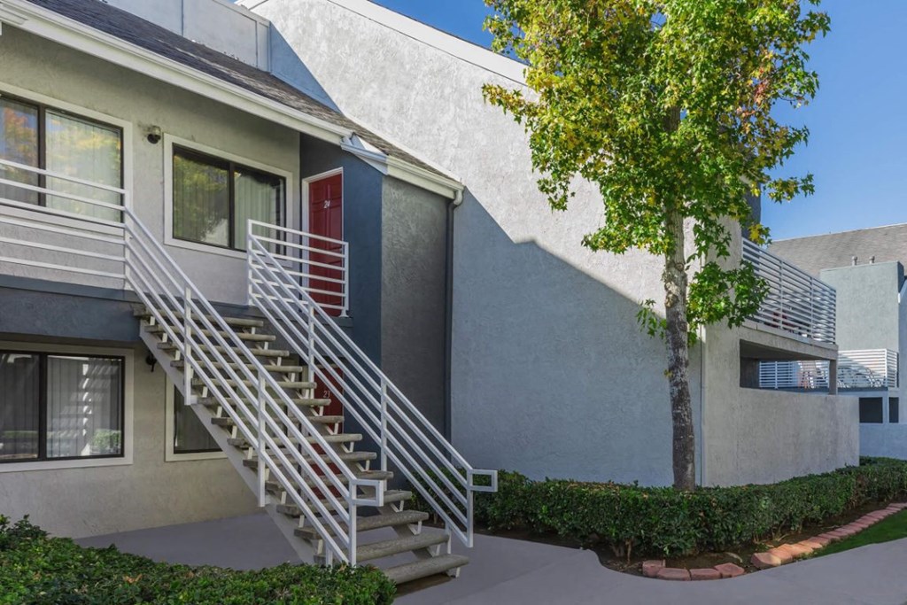an apartment building with stairs and a red door