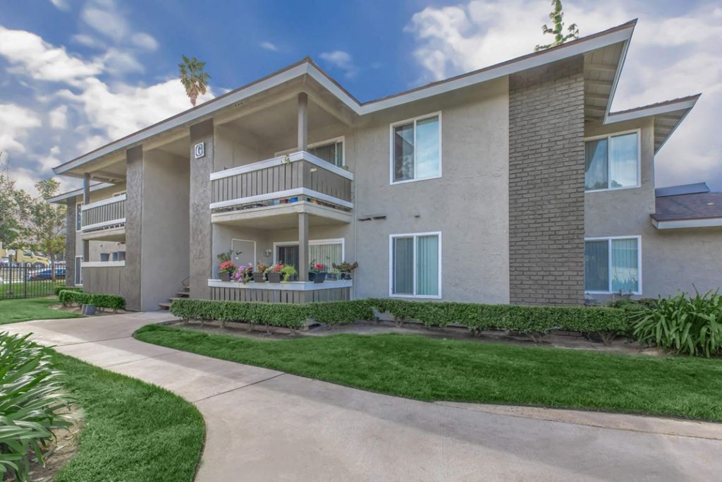 an exterior view of an apartment building with a sidewalk and grass