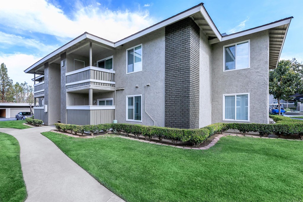an apartment building with green grass and a sidewalk