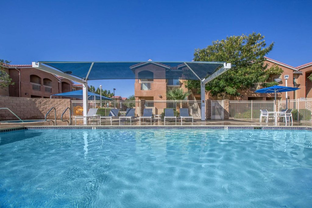 A swimming pool with a blue canopy and chairs around it.