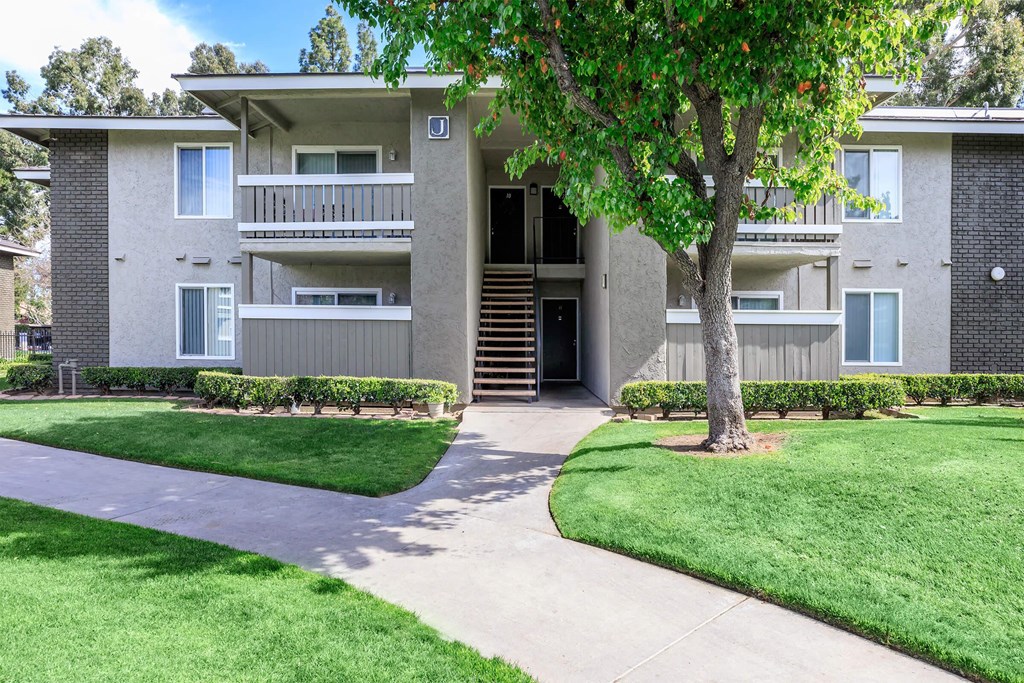 a sidewalk in front of an apartment building with grass