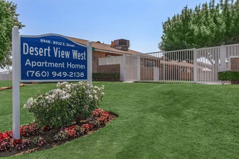 A sign for Desert View West Apartment Homes stands in a well-manicured garden.