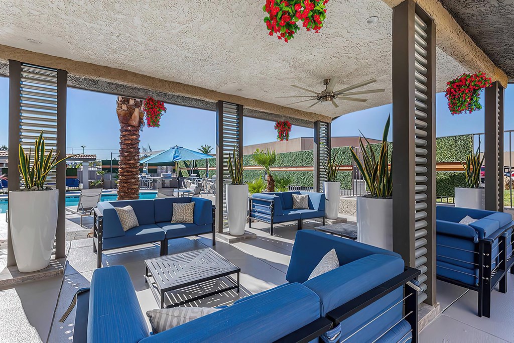 a patio with blue couches and chairs and a pool