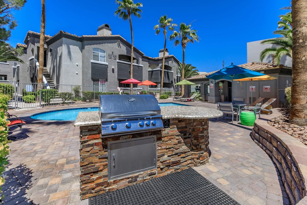 a barbecue grill is next to a swimming pool with a house