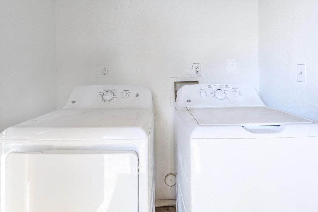 two white washing machines in a white laundry room