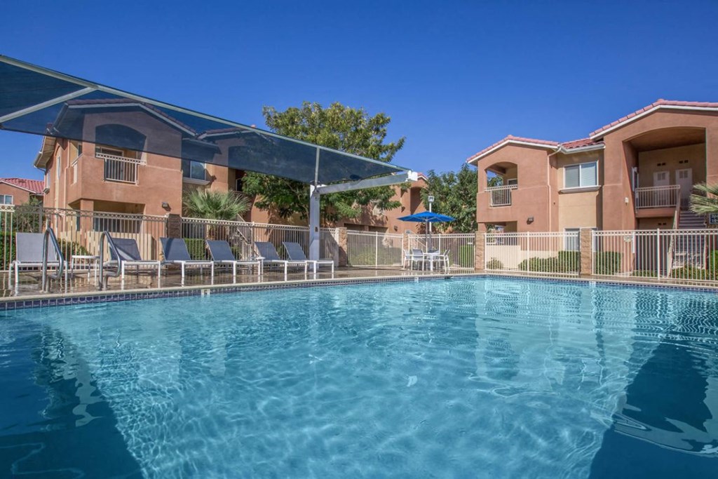 A swimming pool in front of a building with a blue sky in the background.
