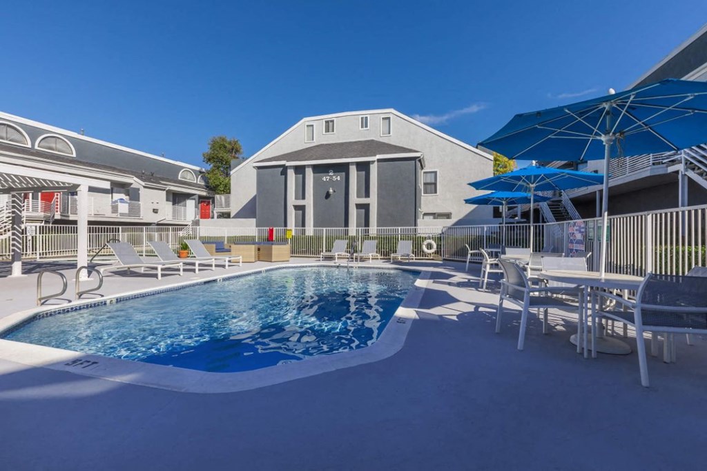 a pool with chairs and umbrellas next to a building