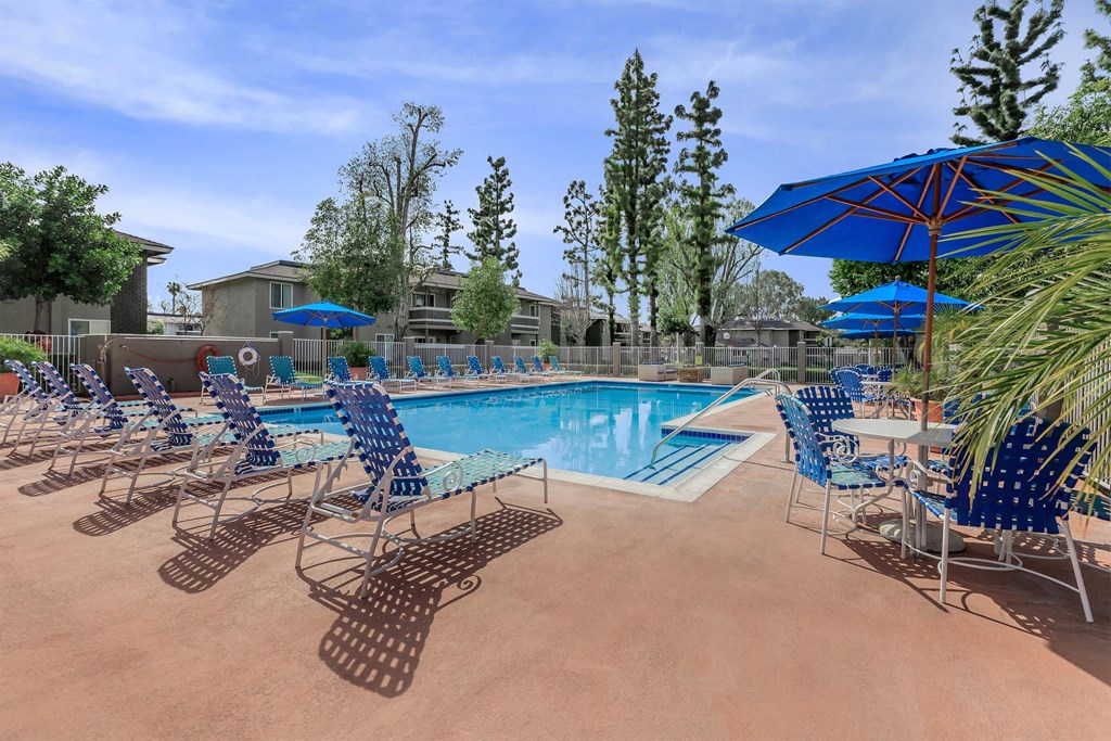 our resort style pool is filled with lounge chairs and umbrellas