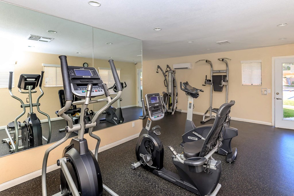 a gym with exercise equipment and mirrors in a home for sale