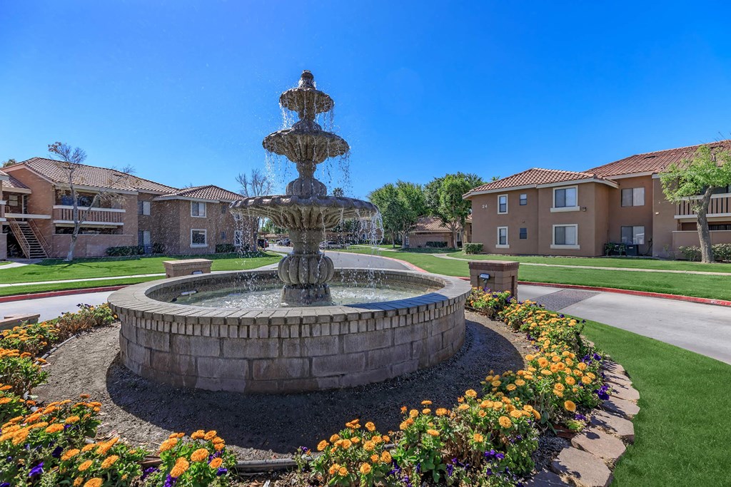a stone fountain in the middle of a park with apartments in the background