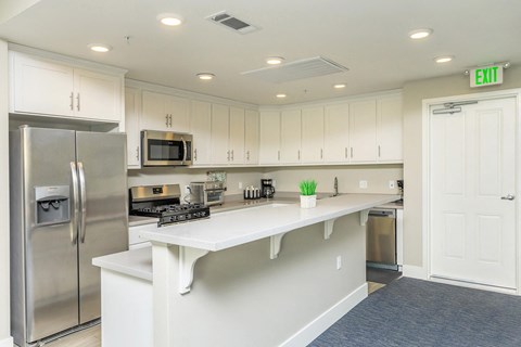 A kitchen with white cabinets and a stainless steel refrigerator.