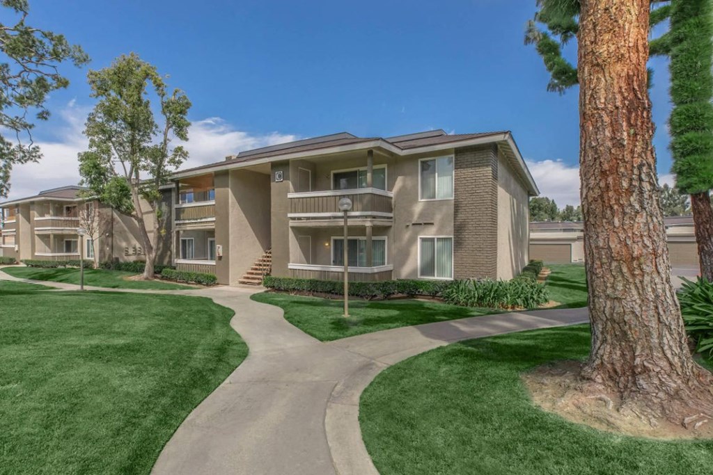 an exterior view of an apartment building with trees and a sidewalk