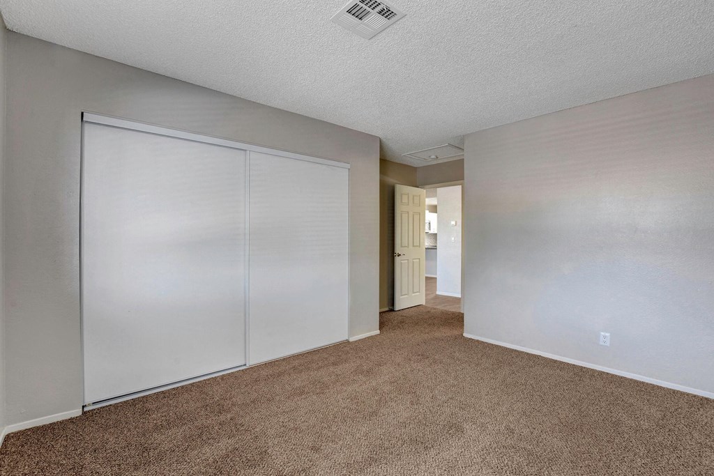 a bedroom with white closets and a carpeted floor