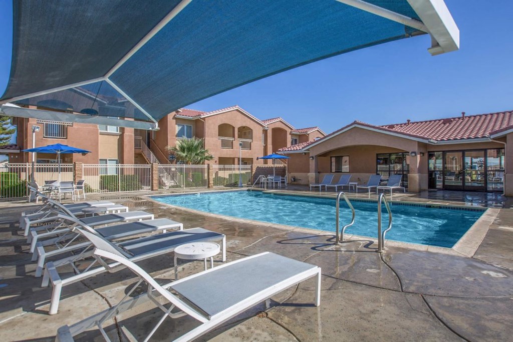 A pool area with sun loungers and a blue umbrella.
