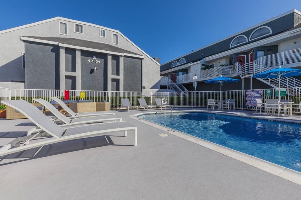 a resort style pool with lounge chairs and a building in the background
