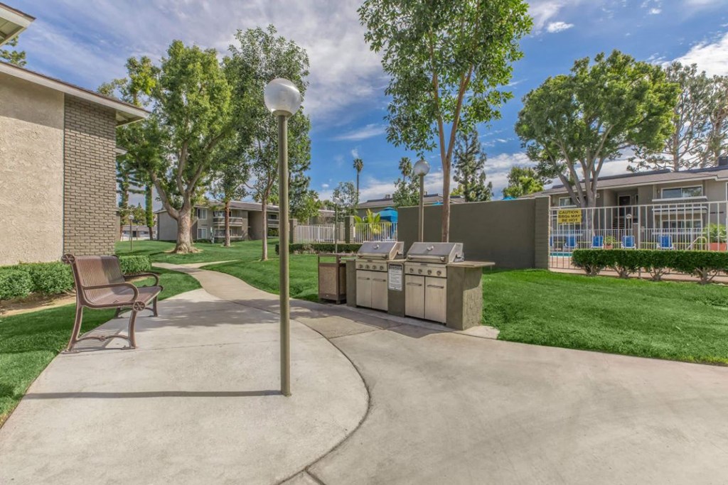a patio with a grill and a picnic table in front of a building