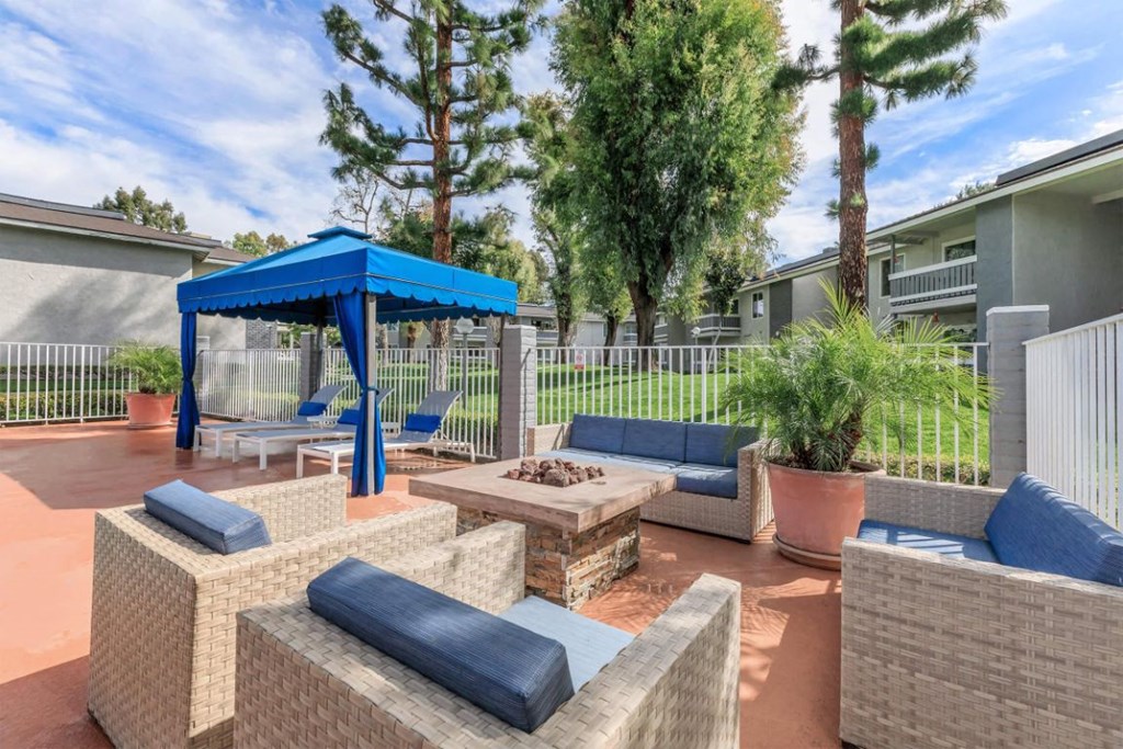 a patio with couches and a table with a fire pit