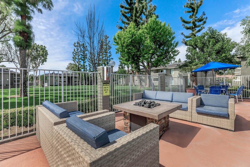a patio with couches and a table with a fire pit