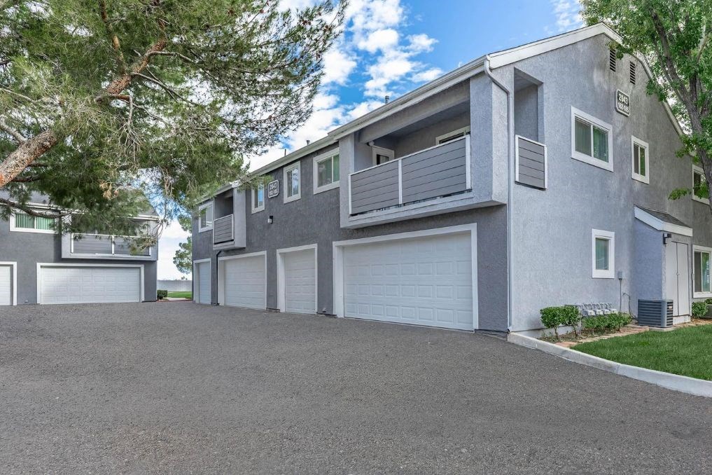 a gray apartment building with a driveway and garage doors