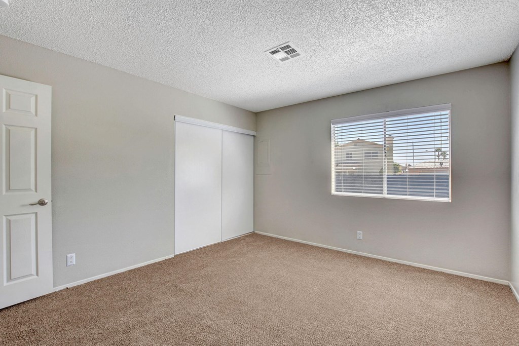 an empty bedroom with a window and a door