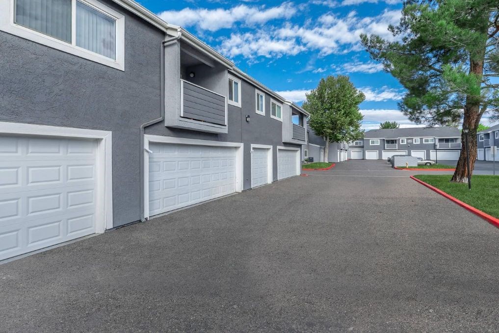 a paved driveway with white garage doors in front of a building