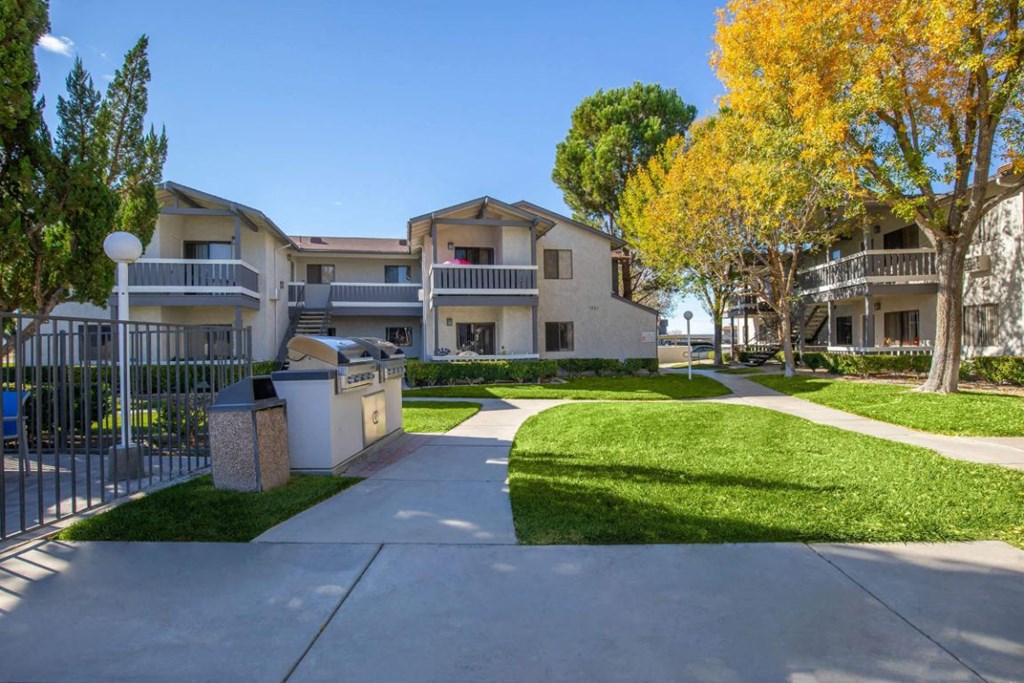 the view of an apartment building with a yard and sidewalk