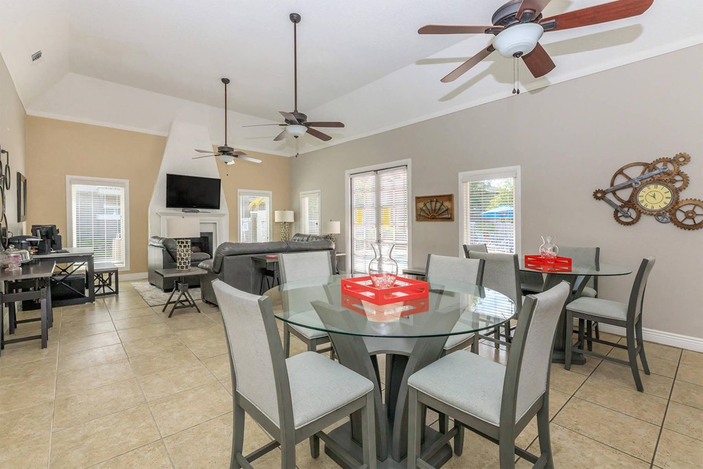 a dining room with a glass table and ceiling fans