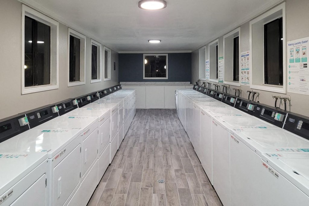a laundry room filled with lots of white washers and dryers
