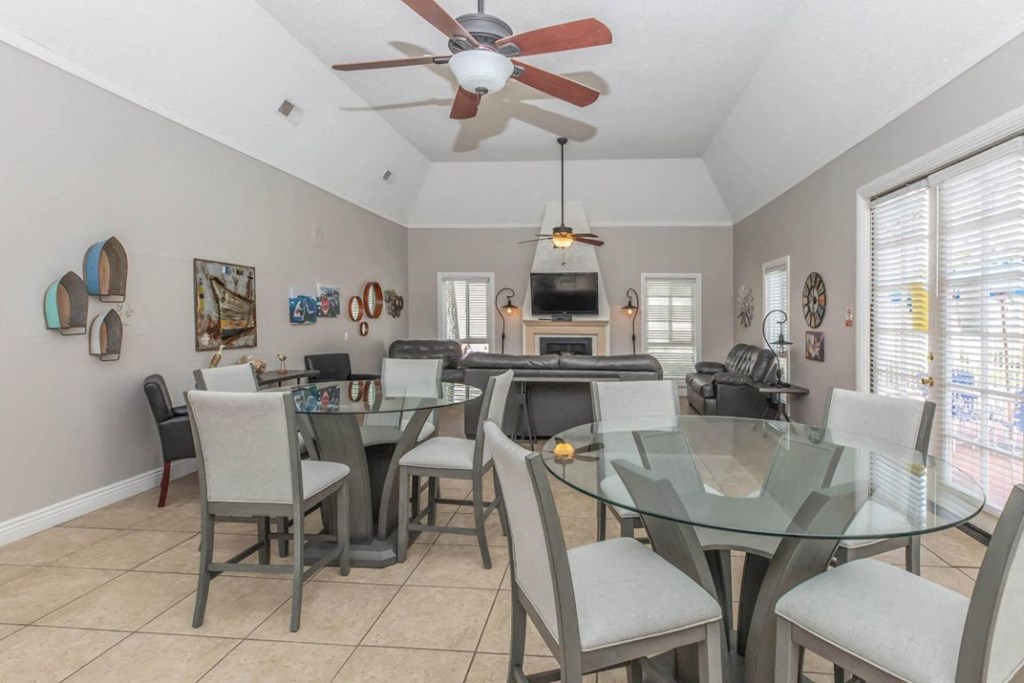 a dining room with a glass table and chairs and a ceiling fan