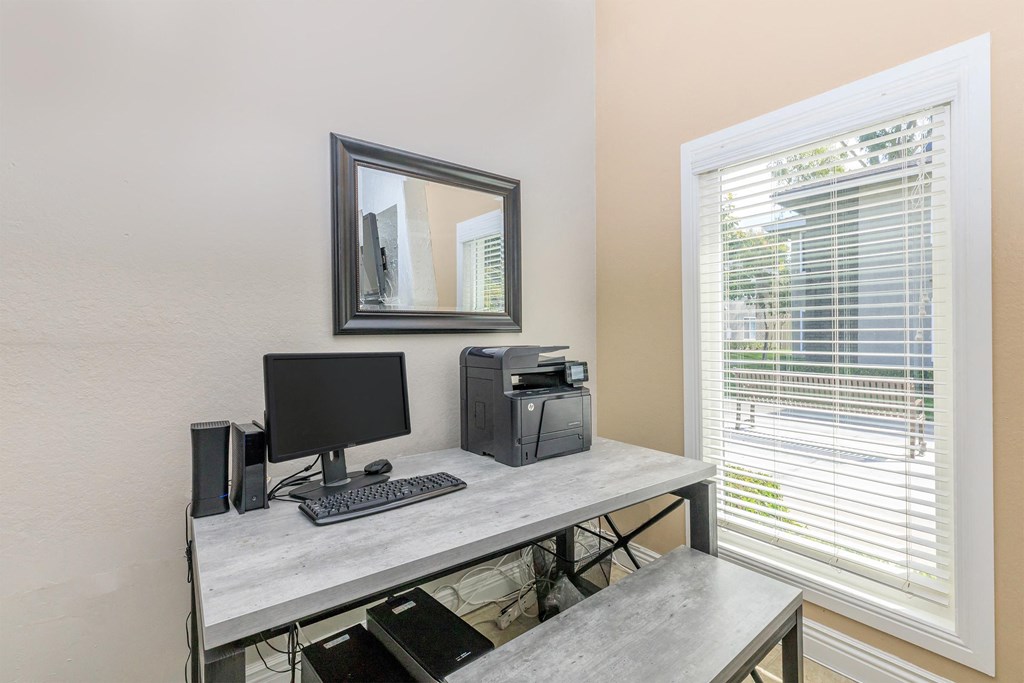 a home office with a computer desk and a window