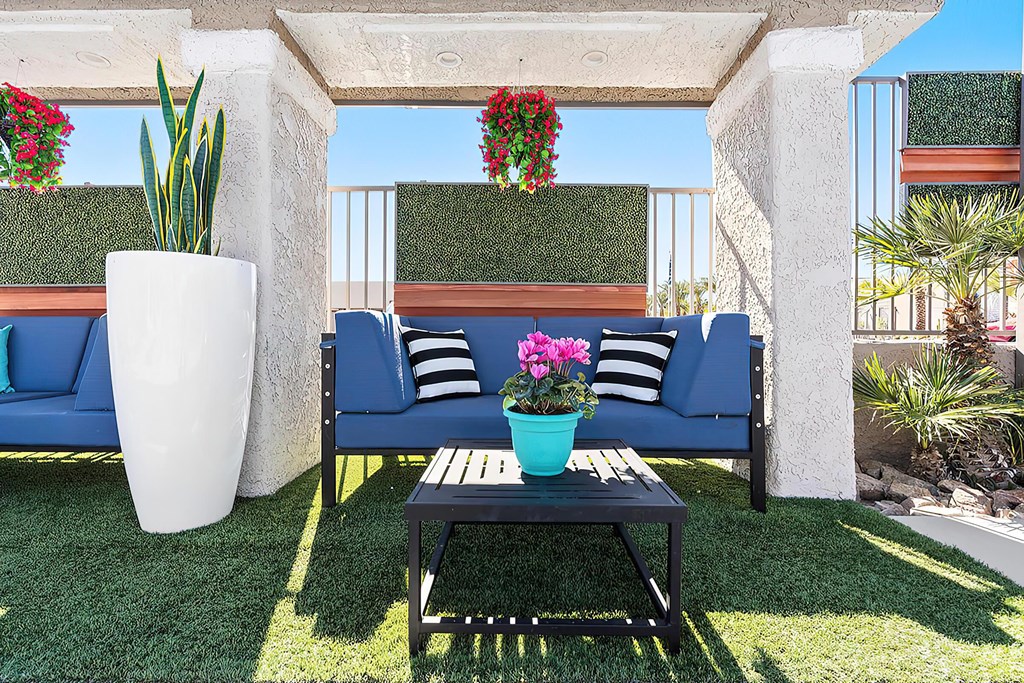 a patio with blue couches and a table with flowers