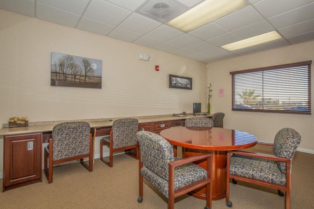 A conference room with a table, chairs, and a painting on the wall.
