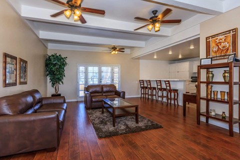 A living room with brown leather furniture and a ceiling fan.