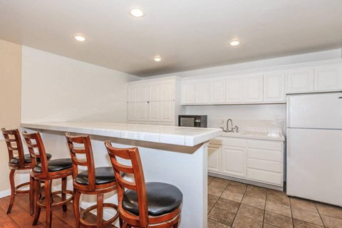 A kitchen with white cabinets and a white fridge.