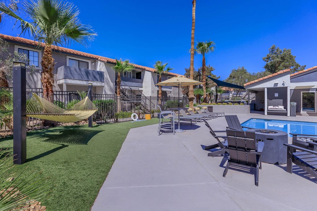 the backyard of a house with a pool and chairs and hammocks